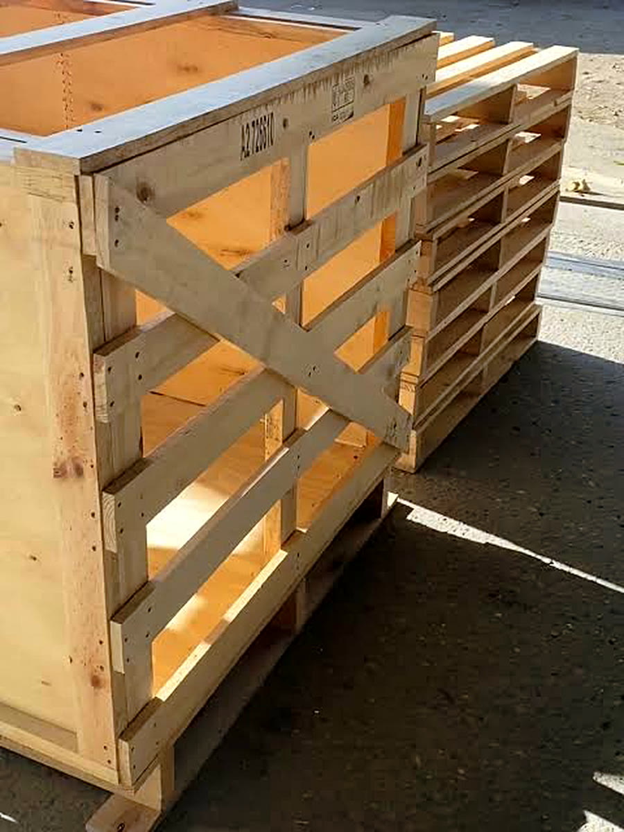 Huacal de madera con refuerzo en cruz junto a tarimas en patio
